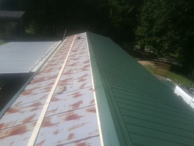 Old rusted panels beside newly installed green metal roofing — Wind Damage Roof Repair by Roofing Brothers in Manasquan