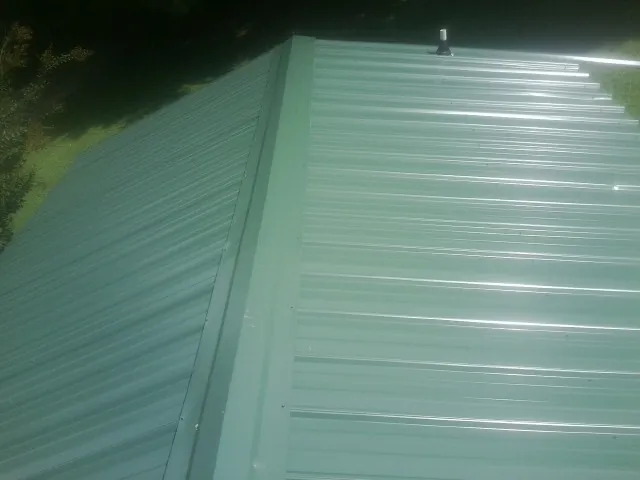 New green metal panels meeting at the ridge of a roof — Flat Roof Repair work by our crew in Manasquan