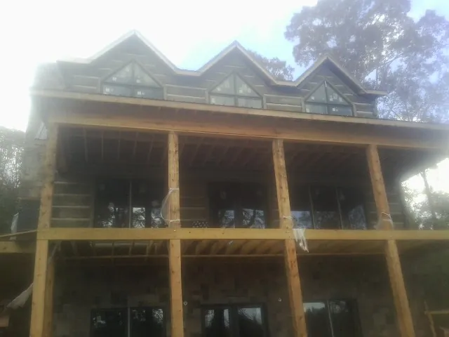 Dormers and porch framing on a large log home under construction — Roof Coating work by our crew in Manasquan