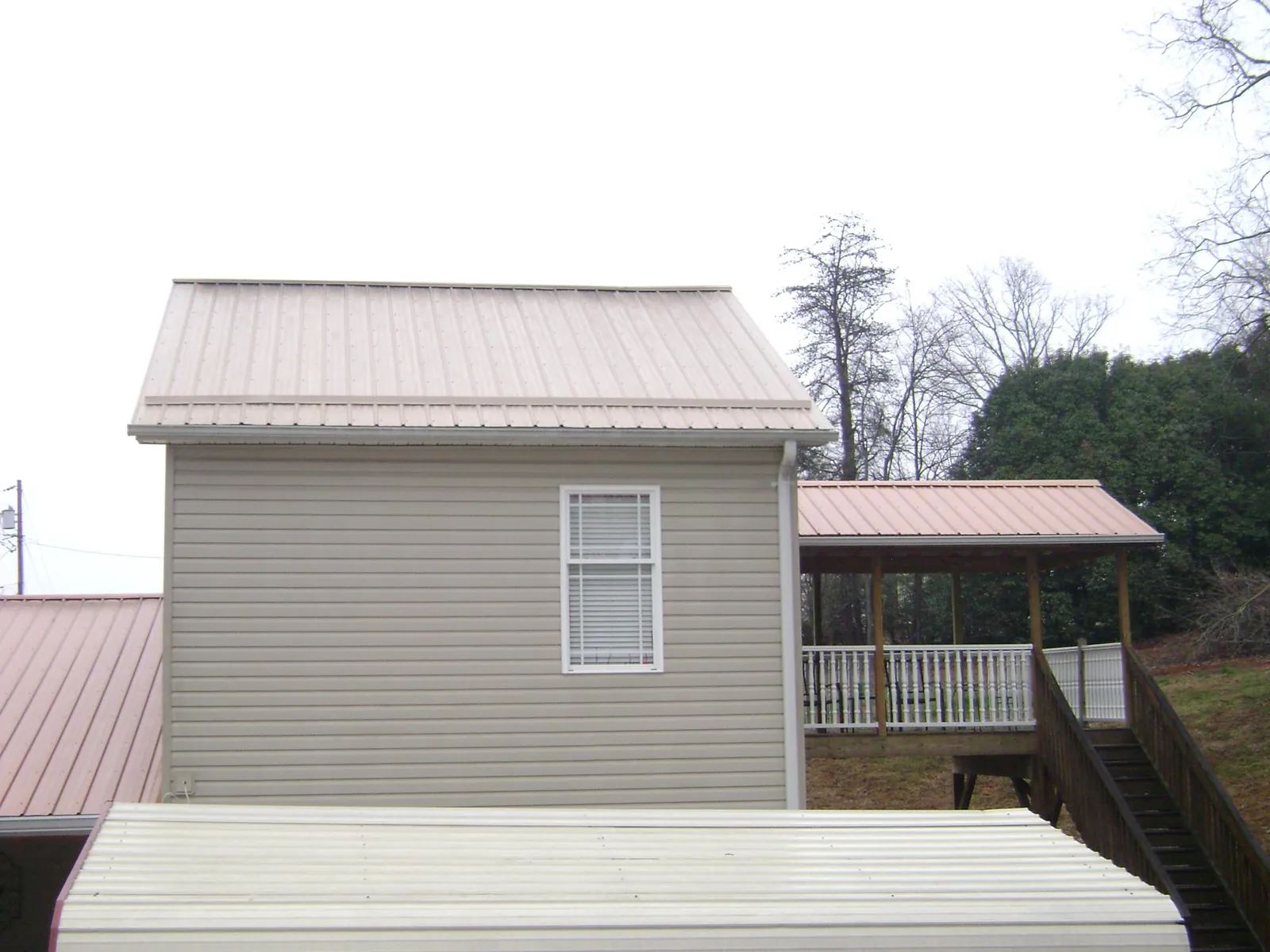 Tan metal roofs on a two story addition and attached porch, from a Roof Replacement job in Manasquan
