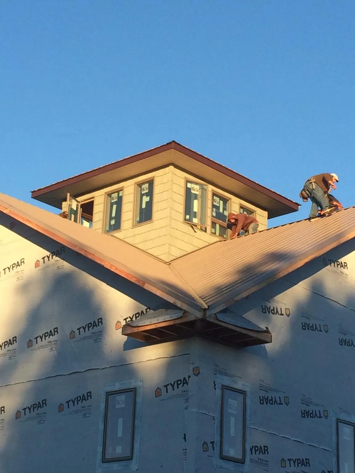 Roofers working around a rooftop cupola on a new metal roof at sunset — Roof Waterproofing in Manasquan by Roofing Brothers
